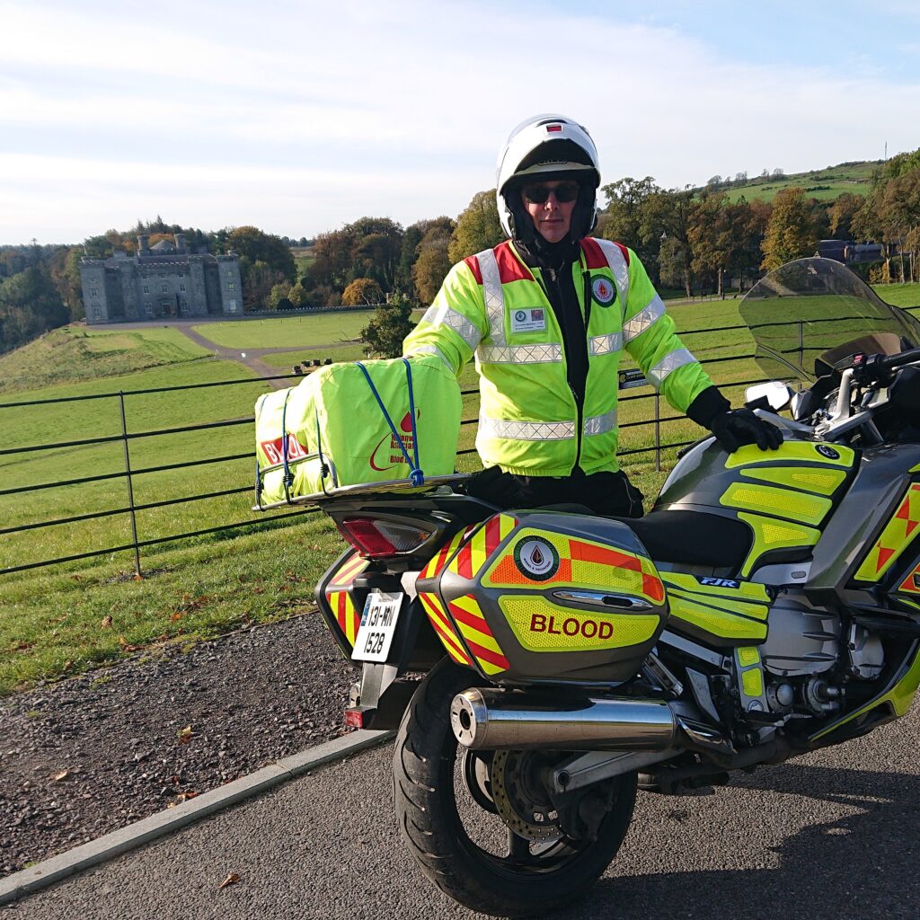 Photo of man in reflective vest standing in front of a motorcycle