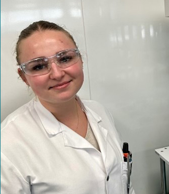 Photo of Lucie wearing goggles and a lab coat