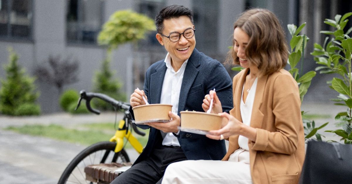 Two employees sitting on a bench outside eating lunch