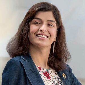 Joti Sidhu, BMS employee and Cancer Support Network (CSN) member. Joti has shoulder length brown hair and is smiling. She wears a navy blue blazer and floral blouse. 