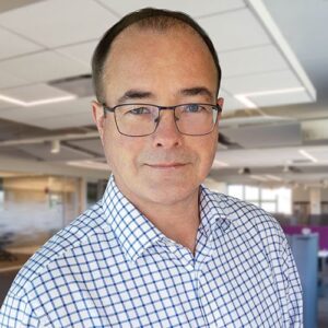 Tom Wells, BMS employee with dark hair, wearing glasses and a pattered shirt.