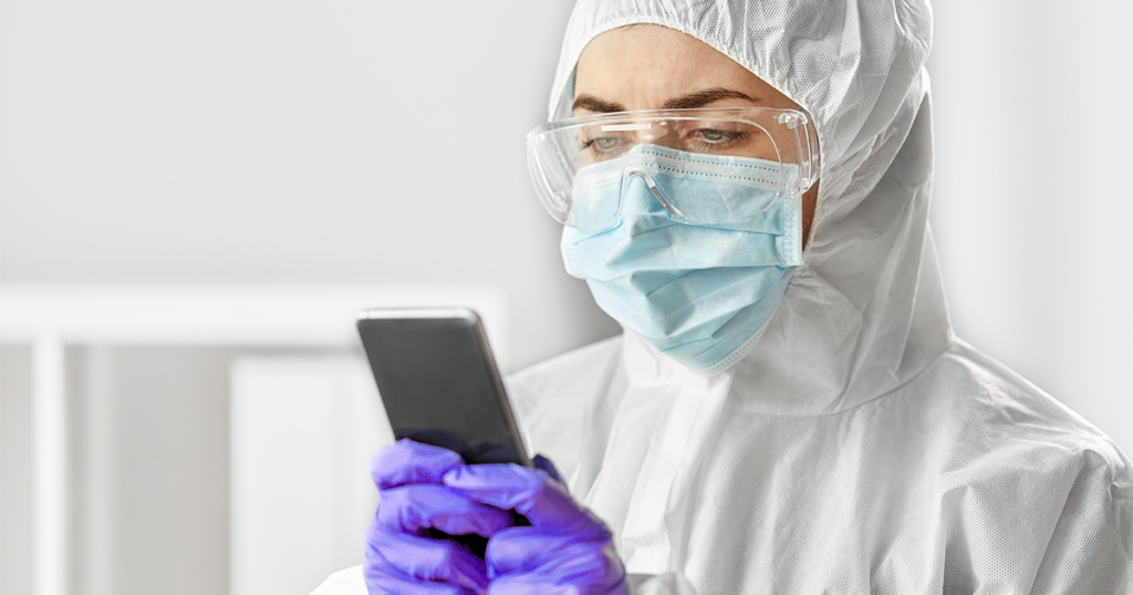employee wearing PPE and holding a device